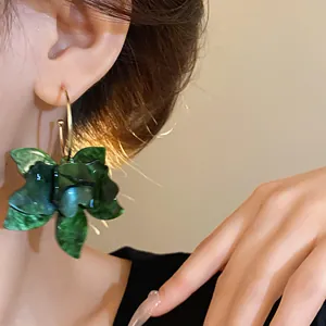 Detailed close-up of elegant vintage green resin flower hoop earrings worn on a model's ear
