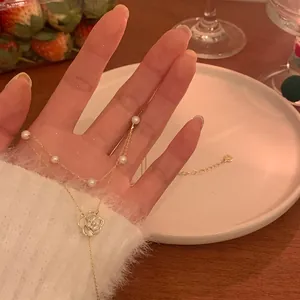 Elegante Gold-Perlenkette mit filigranem weißem Kamelien-Anhänger in Nahaufnahme
