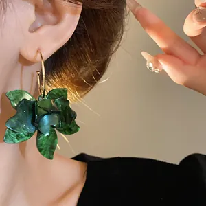 Close-up of vintage green resin flower hoop earring worn by a model in soft light