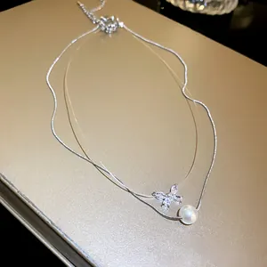 Close-up of double-layer necklace featuring a crystal butterfly and single white pearl