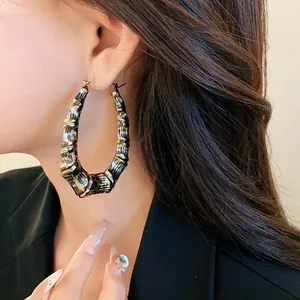 Detailed view of oversized U-shaped bamboo earrings with leopard print pattern on model