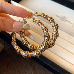 Detailed view of oversized leopard print bamboo style hoop earrings held in hand.