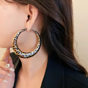 Detailed shot of a stylish leopard print thick hoop earring worn by an elegant model