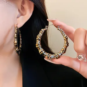 Close-up of leopard print bamboo-textured hoop earrings worn by a model