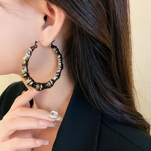 Detail shot of large bamboo-joint hoop earrings with a leopard print patterned finish.