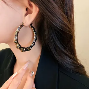 Detailed close-up of stylish leopard print bamboo hoop earrings on a female model