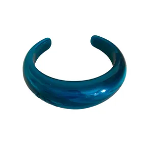 Bracciale rigido in resina blu ottanio traslucido con finitura lucida e design audace.