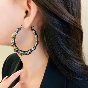 Detail shot of exaggerated leopard print bamboo-style hoop earrings worn by a model