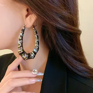 Close-up view of oversized U-shaped hoop earrings with leopard print texture on model