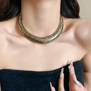 Close-up of geometric U-shaped choker with bold leopard print on gold metal.