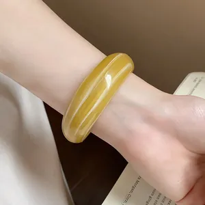 Primo piano di un largo bracciale a fascia in resina marmorizzata gialla sul polso