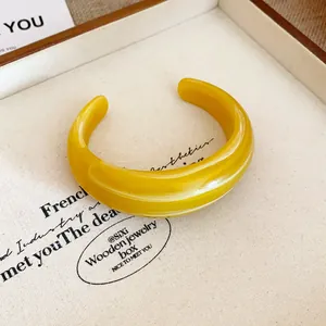 Primo piano di un audace bracciale rigido in resina gialla effetto marmo per donna.