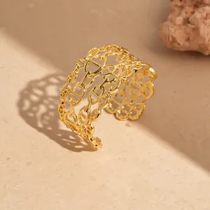 Dettaglio di un bracciale rigido dorato multistrato con design a maglie intrecciate