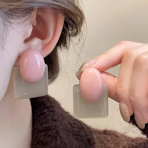 Detailed close-up view of retro pink and grey resin geometric earrings being worn on an ear