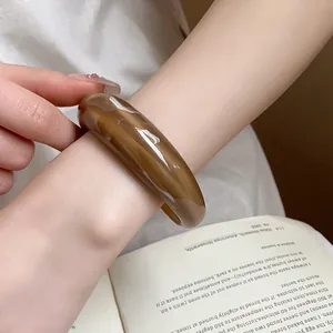 Primo piano di un bracciale rigido in resina marmorizzata ambra al polso