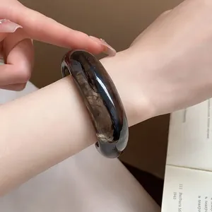 Vista macro che mostra la trama marmorizzata scura di questo bracciale aperto