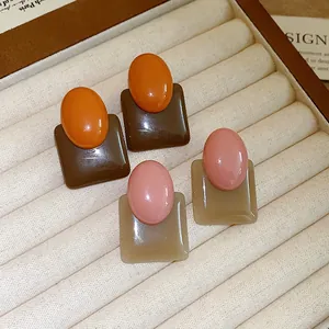 Detailed macro view of retro color-block resin earrings in oval and square shapes