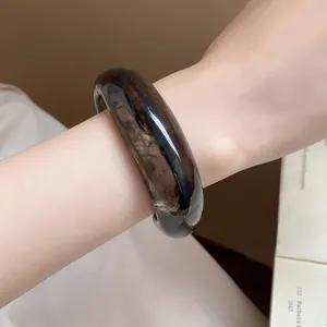 Vista dettagliata di un grosso bracciale rigido aperto marmorizzato marrone scuro lucido