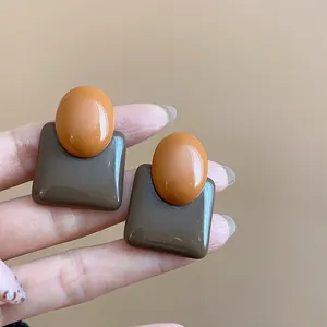 Detail showing vintage resin contrast color stud earrings with glossy finish texture
