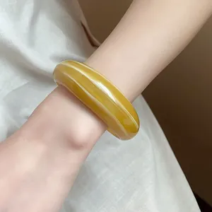 Vista macro dettagliata di un ampio bracciale rigido in resina marmorizzata ambrata
