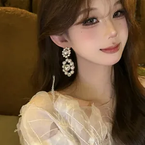 Elegant close-up of pearl and cubic zirconia drop earrings worn by a beautiful model
