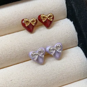 Macro view of gold-plated heart-shaped stud earrings with elegant delicate bows