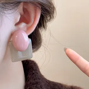 Detailed close-up showing vintage pink oval and grey square resin earrings on ear