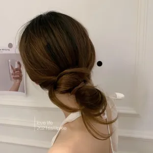 Detail showing a minimalist brown hair tie used for a stylish low bun on brown hair.
