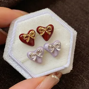 Detailed view of heart-shaped earrings with bow accents in red and purple color variants
