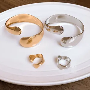 Close-up of minimalist irregular smooth open bangles and rings in gold and silver finish