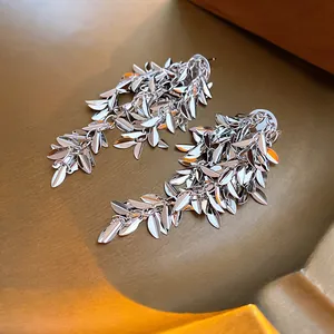 Detailed close-up of silver metallic wheat leaf tassel earrings with a glossy finish