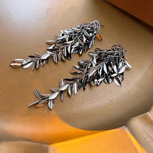Detailed view of metallic leaf tassel earrings in gunmetal finish on golden base