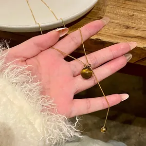 Macro detail of a vintage gold-plated necklace with a polished brown tiger's eye stone bead.