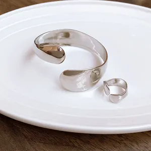Macro view of irregular silver elliptical open bangle and ring with mirror finish