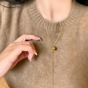 Detailed close-up shot of a gold plated necklace with a round cat-eye stone pendant