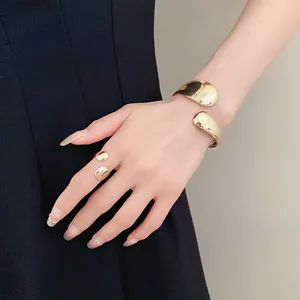 Detail view of gold irregular smooth oval open ring and cuff bracelet set worn on hand