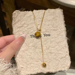 Detailed view of a gold-plated tiger eye necklace displayed on a textured paper card