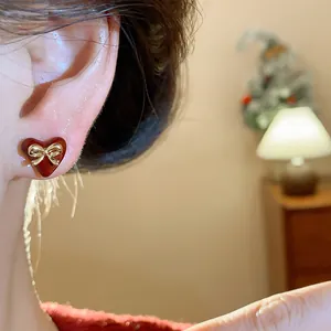 Detailed close-up of a red heart-shaped stud earring with a golden bow accent