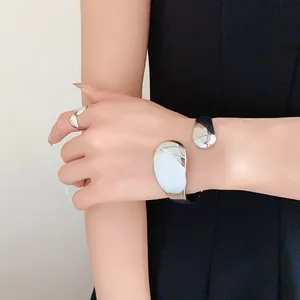Detail of irregular glossy oval open ring and silver cuff bracelet on model.