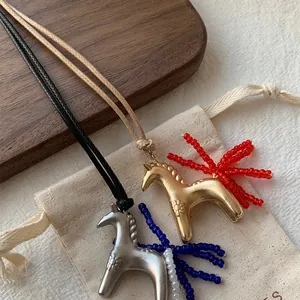 Close-up detail of vintage horse pendant necklaces with beaded tassels on a canvas bag