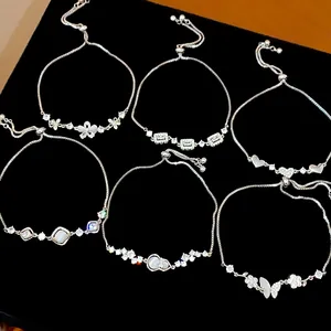 Detail view of a set of various silver zircon butterfly and floral adjustable bracelets