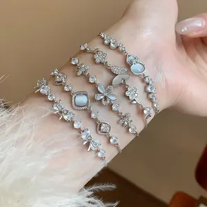 Close-up detail of elegant zircon bracelets featuring butterfly and flower charms.