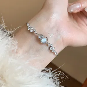 Close-up of a delicate silver flower bracelet with zircons and moonstone charm on a wrist.