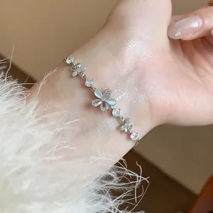 Close-up of exquisite silver bracelet with zircon butterfly and flower charms on wrist