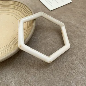 Macro view of a vintage hexagonal resin bangle with creamy white marble texture finish