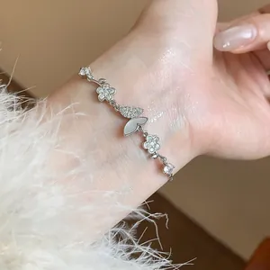 Detail of a delicate silver-tone bracelet featuring zircon butterfly and flower charms.
