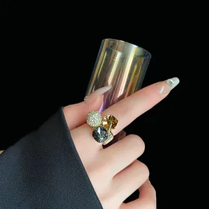 Close-up of geometric zircon open ring with gray and amber crystals on model's hand.