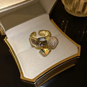 Close-up of a gold-plated open ring featuring geometric zircon stones in a jewelry box
