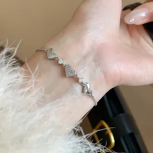 Detailed close-up of a elegant silver heart-shaped zircon bracelet on a woman's wrist.