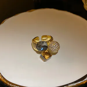 Close-up view of geometric gold plated ring with multicolor stones and zircon ball